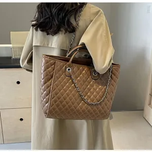 Quilted brown leather tote bag worn as a shoulder bag in a stylish minimalist interior