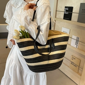 Large black and white striped straw bucket bag with black leather handles for beach vacation