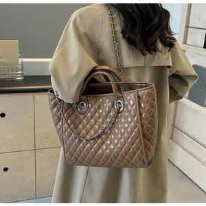 Rear view of model wearing a brown quilted tote bag with chain strap and dual handles