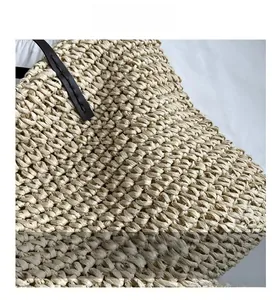 Detail showing cross-weave straw texture and brown leather strap on a summer tote