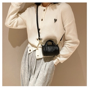 Detail of black mini cylinder crossbody bag with lychee grain texture and dual handles