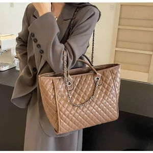 Detail of quilted caramel tote bag featuring golden chain strap and large capacity