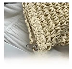 Detailed macro view of the smooth silver zipper closure on a beige woven straw tote bag