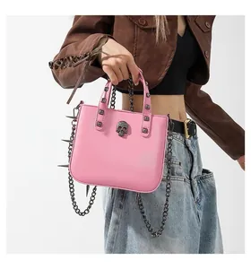 Detailed view of pink punk handbag with metal skull emblem and spiked chain strap