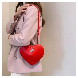Détail du sac à bandoulière en cuir rouge en forme de cœur avec pendentifs trèfles