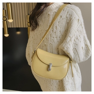 Dettaglio di una borsa a sella crema minimalista con fibbia argentata e tracolla