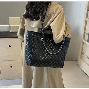 Quilted tote bag with chain strap shown on model wearing a trench coat for daily styling