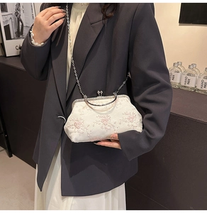 Close-up of elegant floral embroidery and vintage metal clasp on a white lace handbag