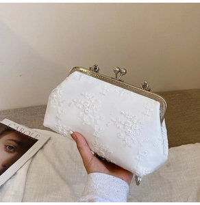 Close-up of white floral lace embroidery on vintage style evening clutch bag with gold clasp