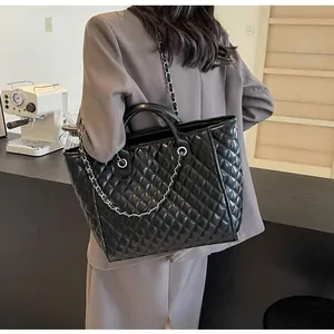 Macro shot of black quilted tote bag with chain strap and shiny leather texture details