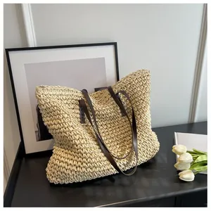 Detail of handwoven straw tote with premium brown leather handles in a luxury setting