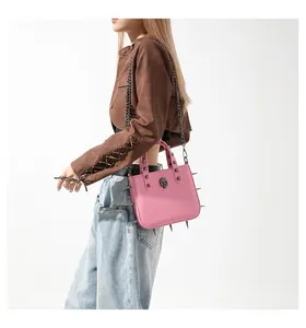 Detail of pink punk crossbody bag featuring gothic studs and a black skull relief design