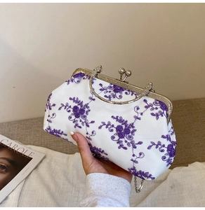 Detail view of purple floral embroidery on white fabric with metal frame and sphere clasp