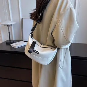 Detail of white crescent crossbody bag with grain leather texture and wide strap