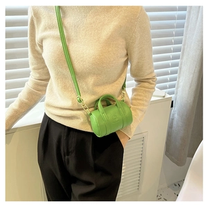 Close-up of grass green mini cylindrical crossbody bag with litchi grain leather texture