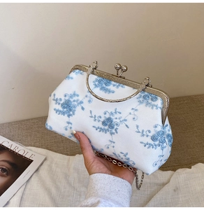 Detail view of exquisite blue floral embroidery on white vintage frame clutch handbag