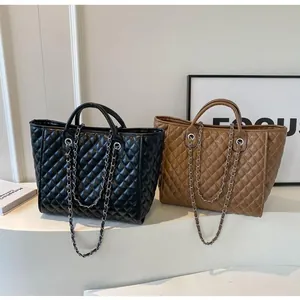 Detailed view of large quilted tote bags with chain straps in black and tan leather