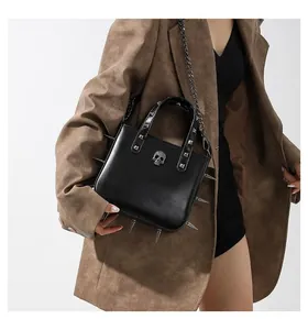 Gothic punk handbag with silver skull charm, metal spikes, and thick chain on brown suit