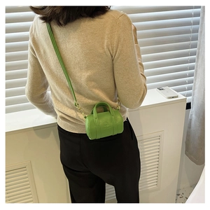 Detail of bright green mini cylindrical bag with pebbled leather texture and metal clasps