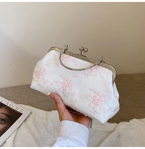 Close-up of white lace floral embroidery on a vintage evening bag with a metal clasp