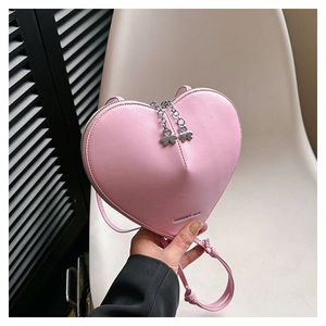 Détail d'un sac bandoulière rose en forme de cœur avec fermeture éclair fleurie