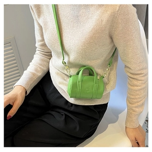 Close-up of a green lychee pattern leather cylinder bag with gold metal hardware