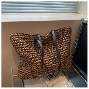 Detail of handcrafted large straw tote bag with brown leather handles and zipper closure