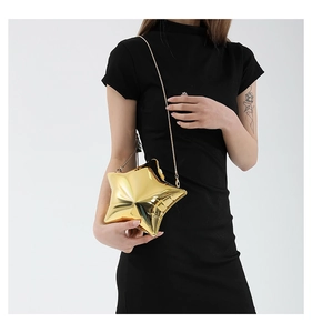 Detail of a shiny gold star-shaped acrylic evening bag with a sleek metal chain strap