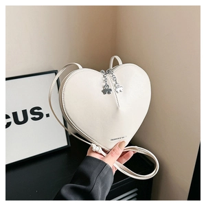 Détail du sac à bandoulière en forme de cœur avec breloques trèfle et lettrage embossé