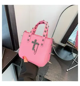 Detail of hot pink gothic handbag featuring metal cross charms and silver studs