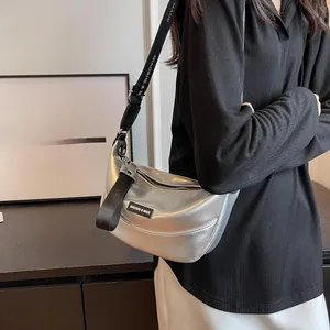 Silver crescent shoulder bag featuring metallic leather texture and wide woven strap