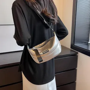 Silver metallic crescent crossbody bag featuring adjustable wide strap and pleated texture
