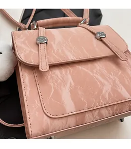 Detail of pink glossy pleated bag featuring metal rivets and soft white plush charm