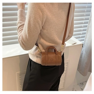 Detailed back view of a brown pebbled leather mini cylinder crossbody bag with gold hardware