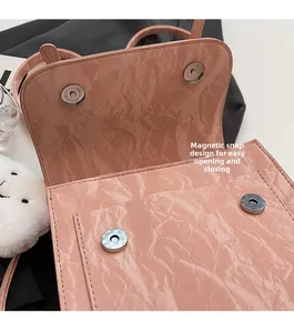 Detail of pink crinkled patent leather bag showing double magnetic buckle closure