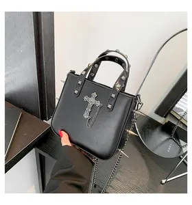 Gothic black leather handbag detail with metal rivets and large silver cross ornament