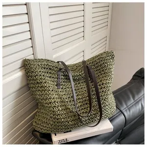Detail of olive green woven straw tote bag featuring sturdy dark brown leather handles