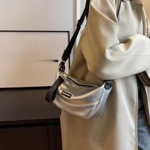 Close-up of a silver crescent crossbody bag with adjustable wide fabric strap