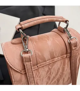 Close-up of pink pleated handbag featuring premium silver metal buckle and hardware