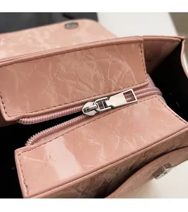 Detail of silver smooth zipper hardware on pink glossy textured leather backpack