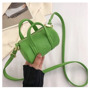 Close-up of grass green litchi grain cylindrical handbag with gold hardware and logo