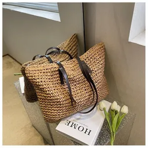Close-up of woven straw tote bag featuring brown faux leather straps and fine texture