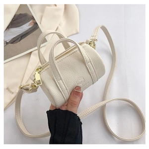 Detailed macro view of off-white lychee texture on a mini cylindrical crossbody bag