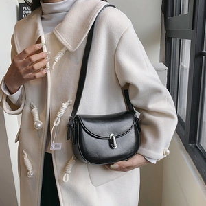 Elegante borsa a sella nera con fibbia in metallo argento e tracolla su un cappotto