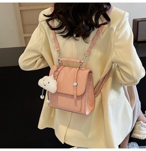 Pink glossy mini backpack with plush cloud charm shown on model in a casual blazer