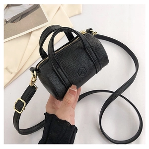 Detailed shot of black mini cylinder bag with lychee grain texture and gold hardware