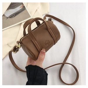 Detailed close-up of a mini brown pebble leather barrel bag held by hand
