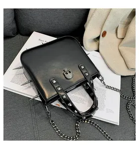 Close-up of black gothic handbag featuring silver skull clasp and sharp metal studs detail