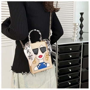 Detail der goldenen Box-Tasche mit Damen-Print, Seidentuch-Griff und Kettenriemen