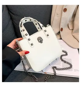 Detail of white gothic punk bag with silver skull ornament and spiked metal chain strap